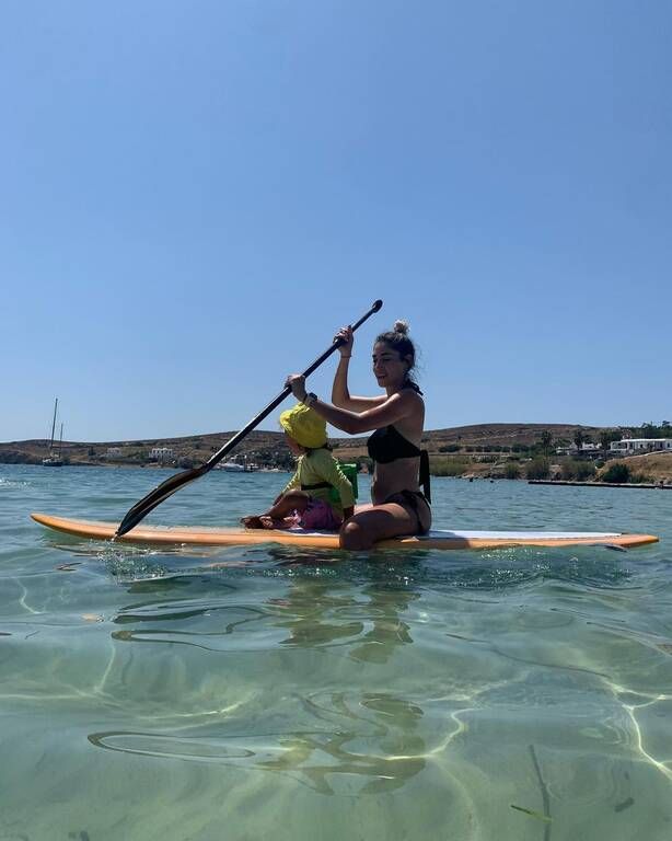 Μαμά και γιος πάνω στη σανίδα απολαμβάνουν τον ήλιο και τη θάλασσα.
