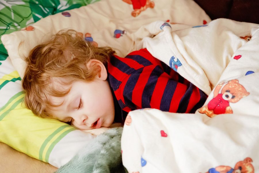 Adorable Little Blond Kid Boy In Colorful Nightwear Clothes Sleeping And Dreaming In His Bed. Health