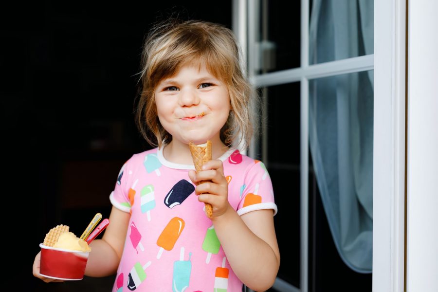 Cute Funny Preschool Girl Eating Fruit Ice Cream At Home. Happy Healthy Toddler Child Smiling And Ta