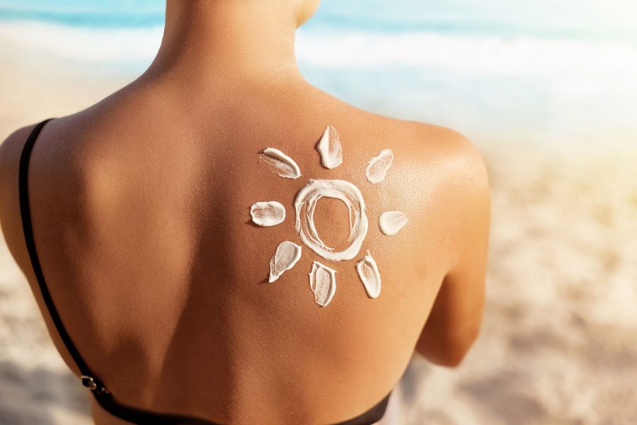 Sun Protection.sun Cream. Woman Applying Sun Cream On Tanned Shoulder In Form Of The Sun. Skin And B