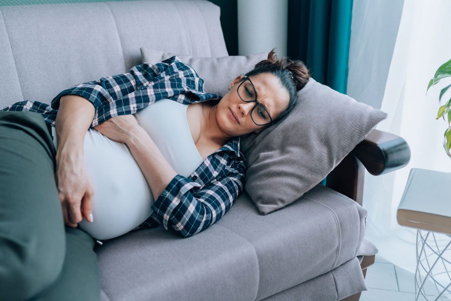 Depression In Pregnancy. Young Sad Lonely Pregnant Woman Lying On Sofa At Home, Having Depressed Moo