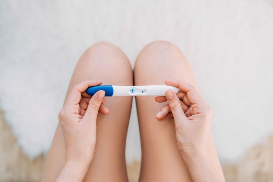 Woman Sit In The Toilet Hold Pregnancy Test. Woman Holding A Pregnancy Test On Her Knees. Pregnancy