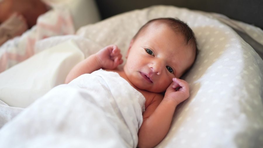 Baby Newborn. Little Baby A Newborn 1 Month Of Life Lies In Bed In The Maternity Hospital. Happy Fam