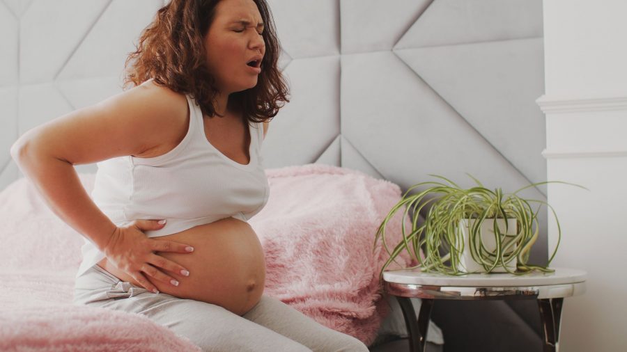 Expectant mother suffering from pregnant pain. Pregnant woman feeling ache lying on a bad. Pregnant
