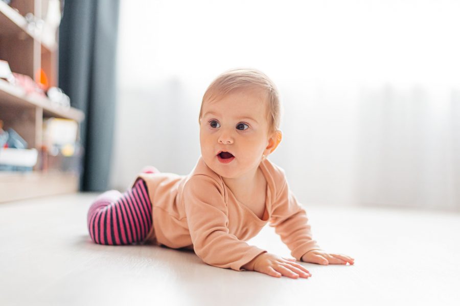Baby Girl Lying On The Floor Learning To Crawl