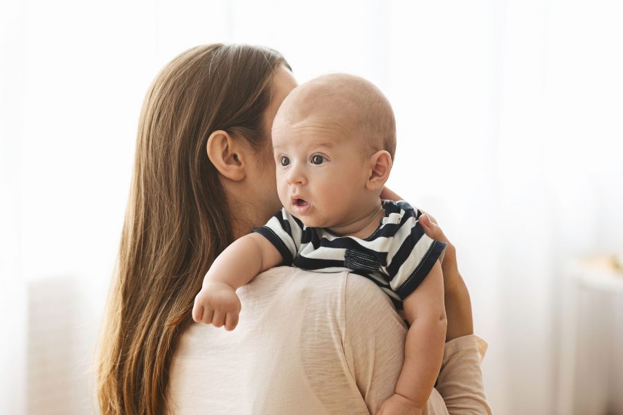 Burping Your Baby Concept. Woman Holding Newborn Baby On Hands And Patting His Back After Breasfeedi