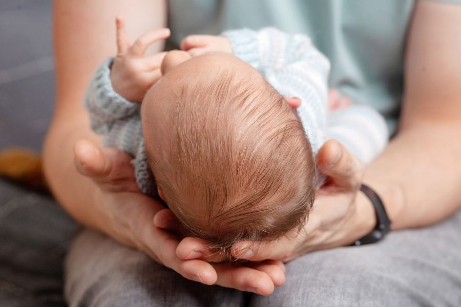 Father Holding Head Of His Newborn Son In Hands. The Baby On Hands At Dad. Loving Parents Hand Holdi